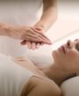 woman performing reiki healing on client in spa.